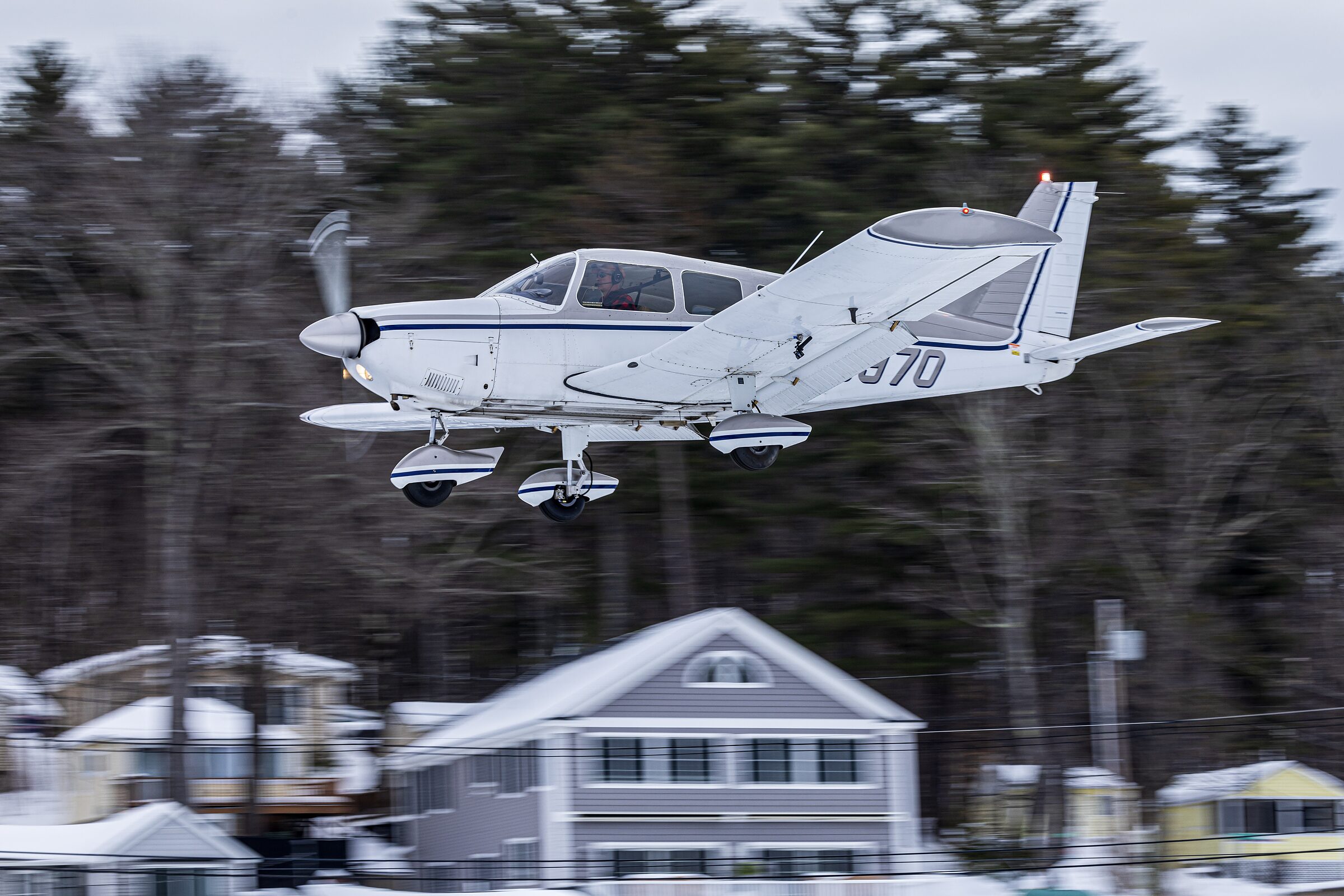 Elaine McPlane on approach above the snowy shoreline with her landing gear down.
