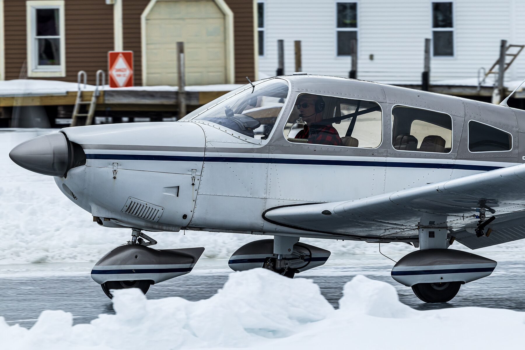 Elaine McPlane taxiing on the plowed ice runway, her pilot visible in the left seat wearing a headset.