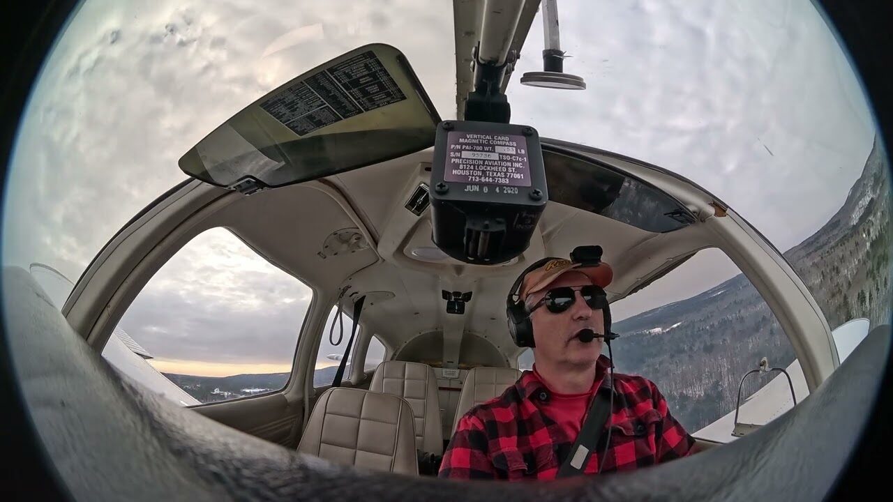 View from inside the cockpit on approach to the ice runway, the pilot at the controls in a red flannel shirt.